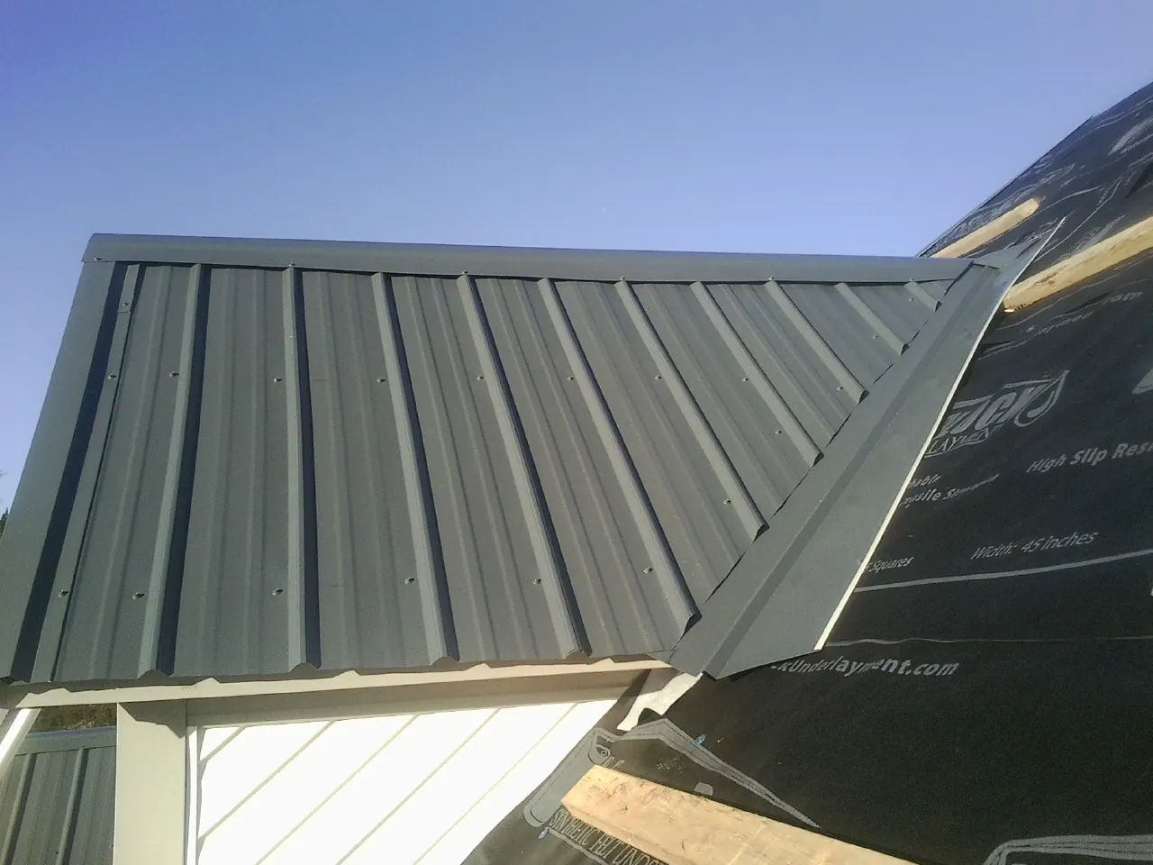 Gray metal roof panels going on over a garage gable in Kellogg