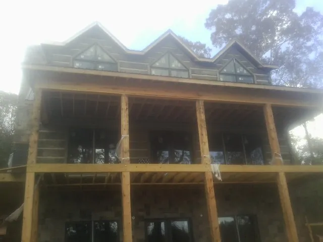 Dormers and porch framing on a large log home under construction — Roof Coating work by our crew in Kellogg