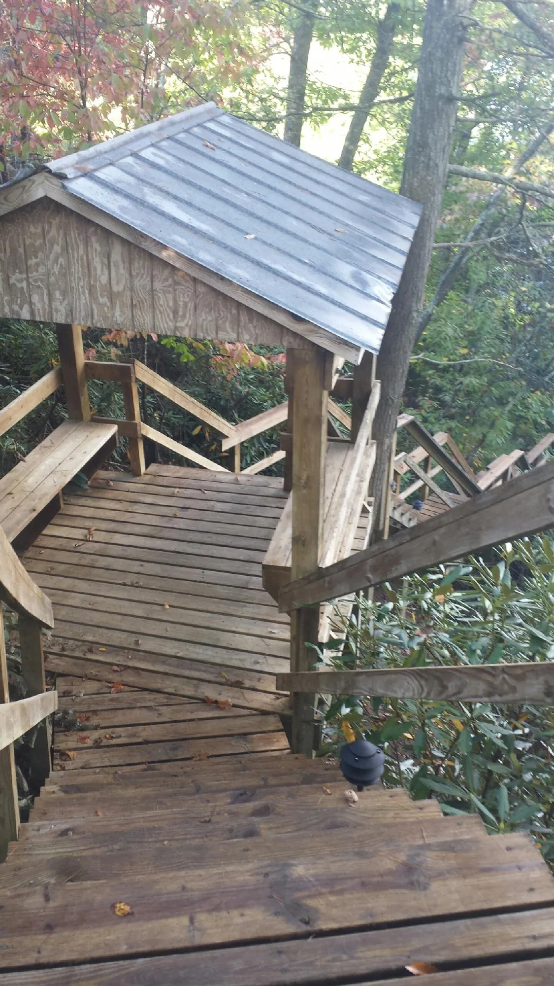 Metal roofed shelter over wooden steps on a wooded walkway — Skylight Repair & Installation work by our crew in Kellogg