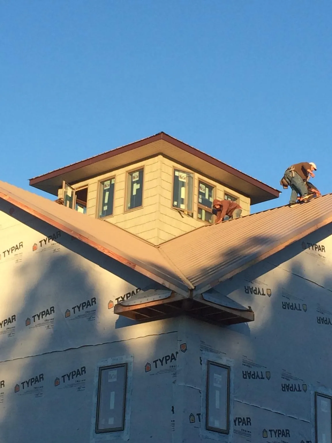 Roofers working around a rooftop cupola on a new metal roof at sunset — Roof Waterproofing in Kellogg by Roofing Brothers
